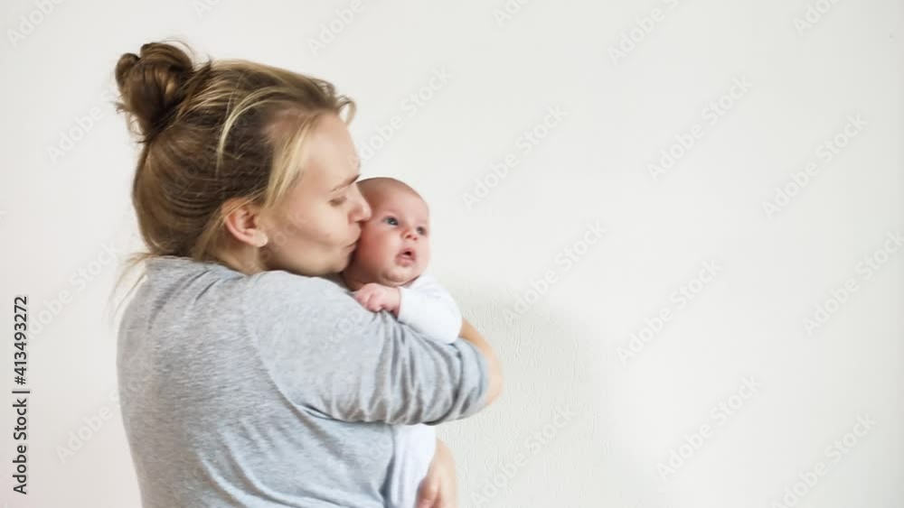 Young smiling and happy mother hold her baby in arms and kissing her forehead. Lifestyle, slow motion. Young smiling and happy mother hold her baby in arms and kissing her forehead. Lifestyle, slow motion.