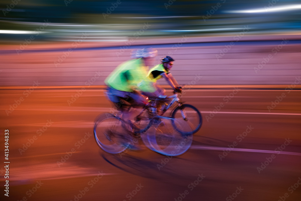 Two blurred cyclists on the road at night