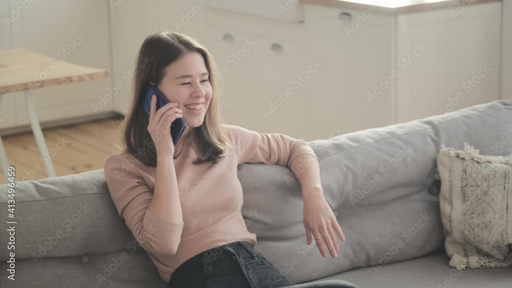 Young woman using smart phone, call sitting on sofa. Millennial lady spending time at home with cell gadget technology. Young woman using smart phone, call sitting on sofa. Millennial lady spending time at home with cell gadget technology.