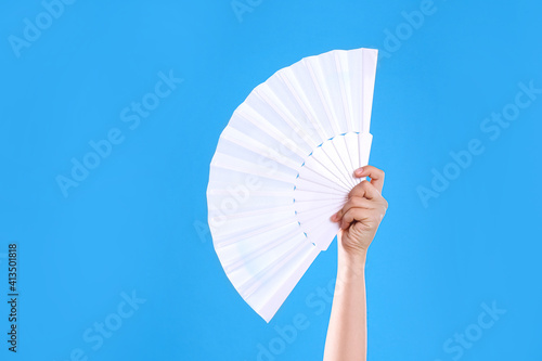 Woman holding white hand fan on light blue background  closeup
