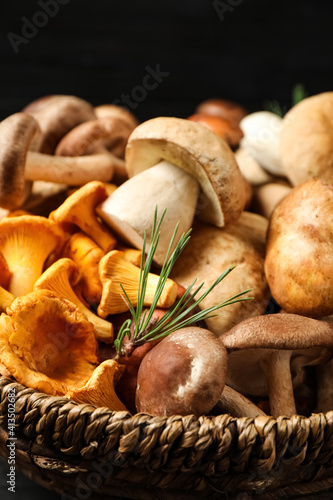 Different fresh wild mushrooms in wicker bowl, closeup