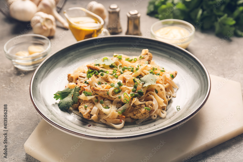 Plate with tasty noodles and chicken on dark background Plate with tasty noodles and chicken on dark background