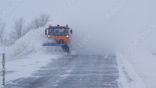 Winter. Heavy snowfall, blizzard. A special car clears the road of snow. Part of the image is blurred.