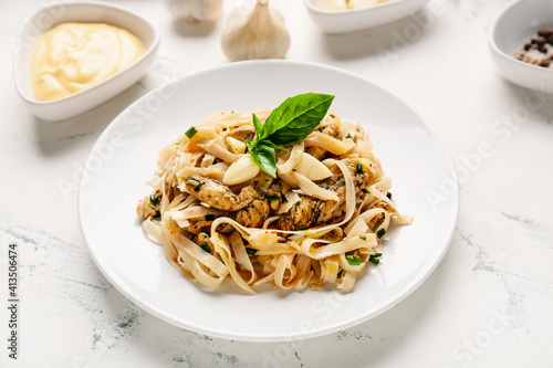 Plate with tasty noodles, chicken and garlic sauce on light background