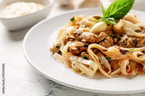 Plate with tasty noodles, chicken and garlic sauce on light background, closeup