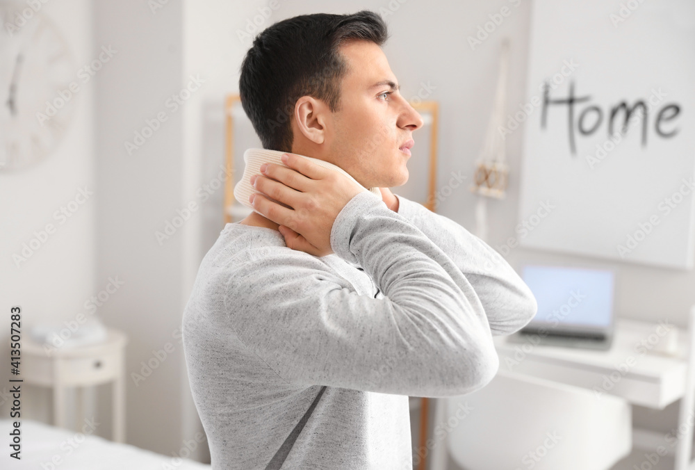 Young man with cervical collar on neck suffering from pain at home Young man with cervical collar on neck suffering from pain at home