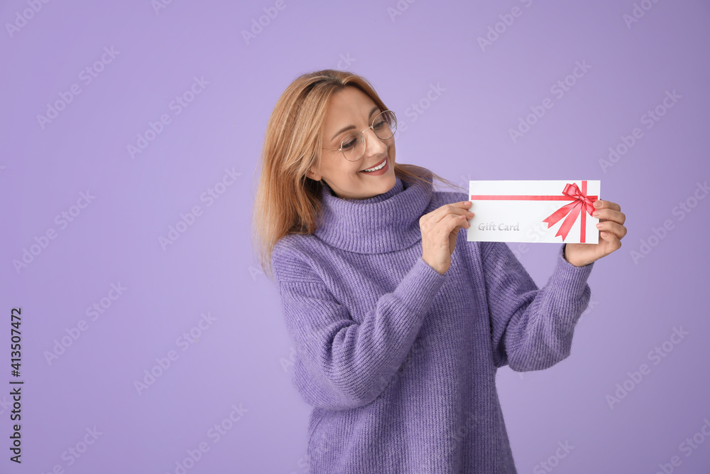 Mature woman with gift card on color background Mature woman with gift card on color background