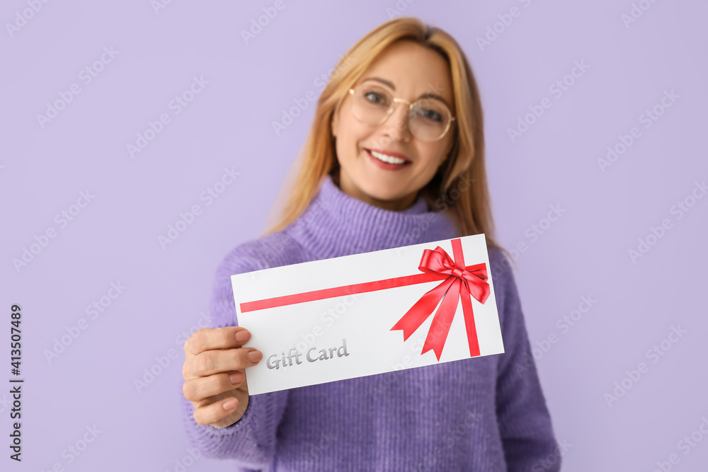 Mature woman with gift card on color background Mature woman with gift card on color background