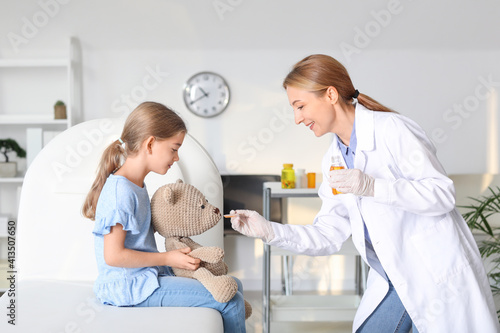 Pediatrician giving medicine to little girl in clinic