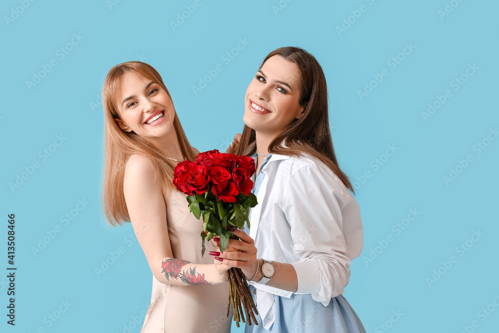 Young transgender couple with flowers on color background. Valentine's Day celebration Young transgender couple with flowers on color background. Valentine's Day celebration