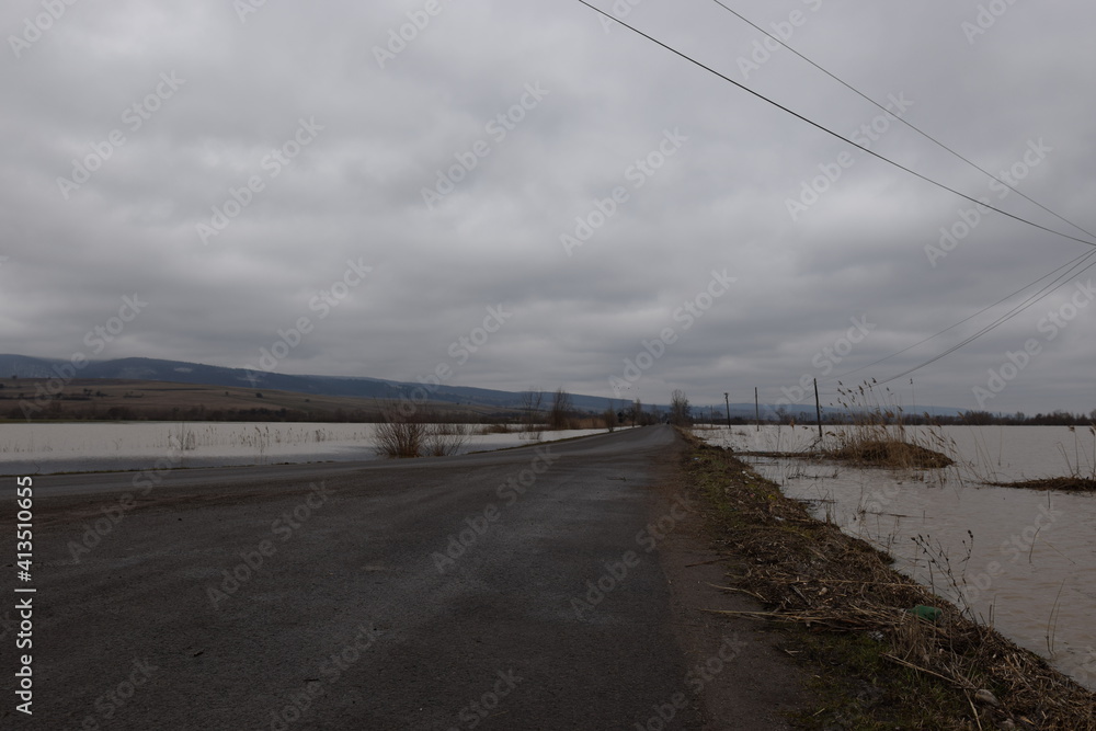 Flooded landscape with wooden poles and grey sky