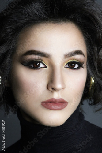 Beautiful young brunette model with bright make-up and curly hair