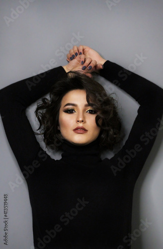 Beautiful young brunette model with bright make-up and curly hair