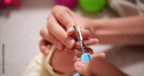 Mom cuts her lettle son nails on hand. A woman uses small baby safety scissors. slow motion photo