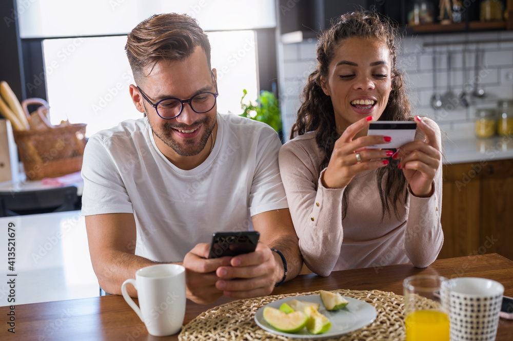 Happy couple using credit card for online shopping at home Happy couple using credit card for online shopping at home