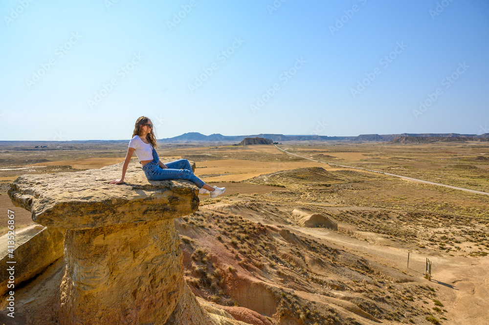 Woman in desert with landscape and old house built of earth