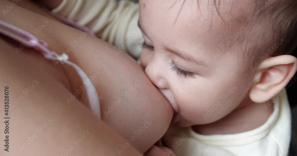 Mother breastfeeding her newborn baby on sofa. Milk from mother's breast is a natural medicine to baby. family, food, child, eating and parenthood concept. slow motion Mother breastfeeding her newborn baby on sofa. Milk from mother's breast is a natural medicine to baby. family, food, child, eating and parenthood concept. slow motion