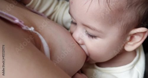 Mother breastfeeding her newborn baby on sofa. Milk from mother's breast is a natural medicine to baby. family, food, child, eating and parenthood concept. slow motion photo