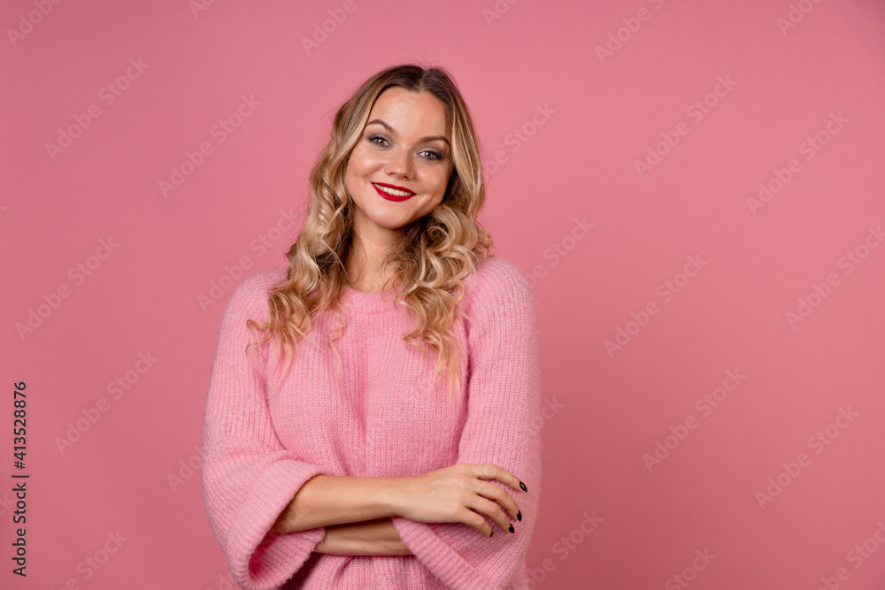 Young attractive woman in a warm pink sweater on a pink background, blonde with curly hair and red lipstick. Studio portrait, copy space Young attractive woman in a warm pink sweater on a pink background, blonde with curly hair and red lipstick. Studio portrait, copy space