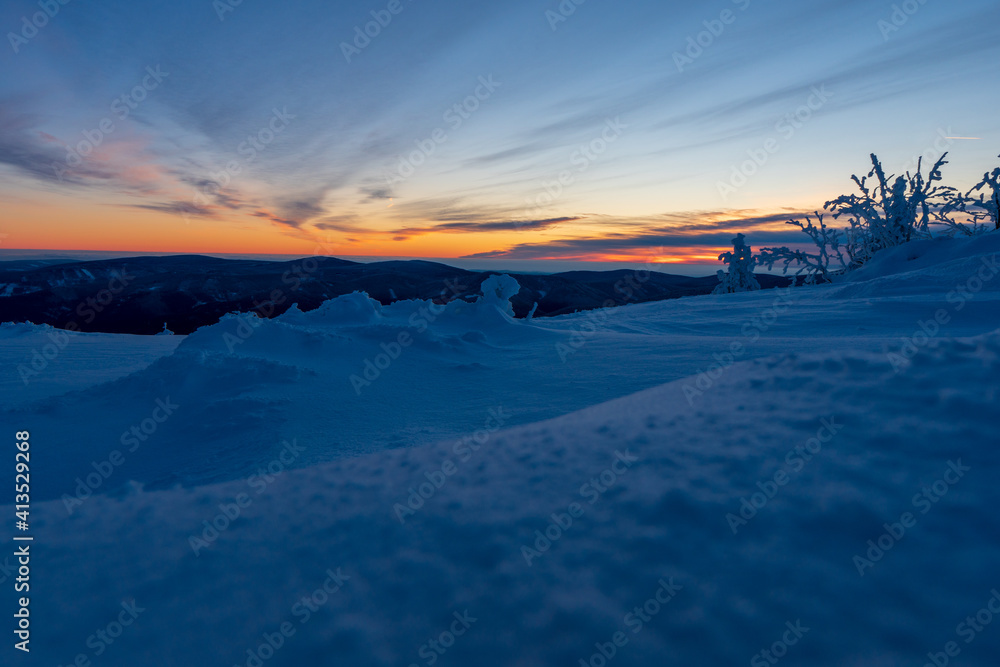 Sunrise or sunset in the winter mountains landscape. Yellow and blue clouds in the morning in czech republick