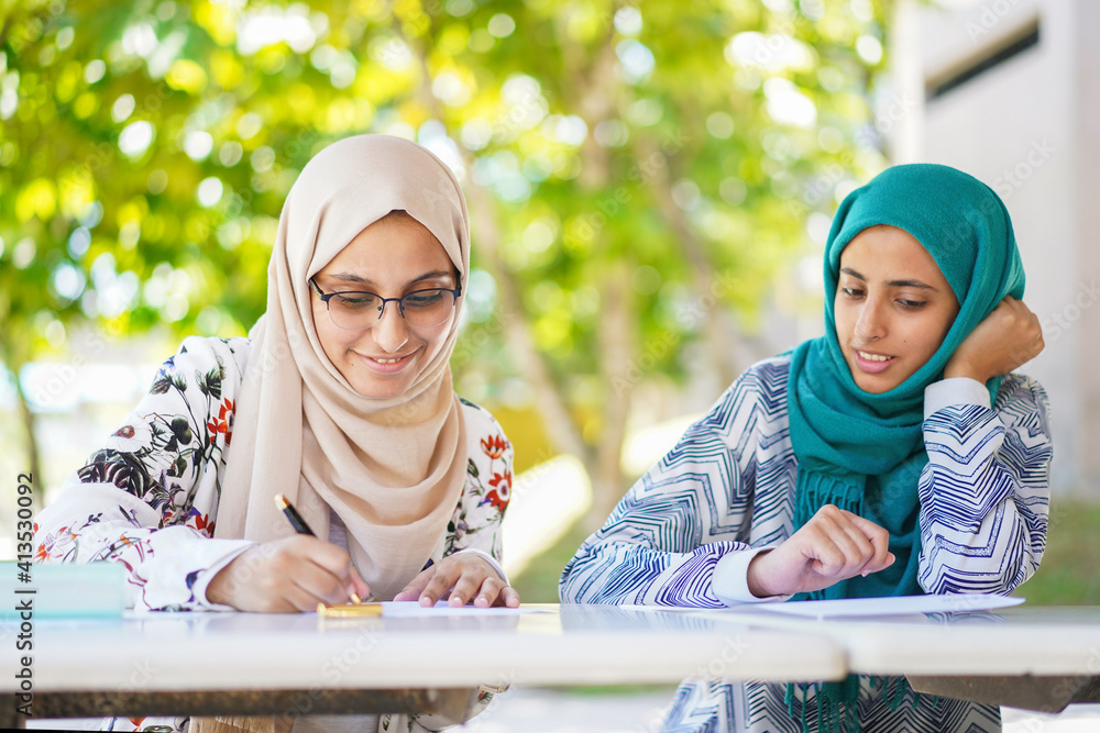 Education concept: Young Muslim students are writing and smiling Education concept: Young Muslim students are writing and smiling