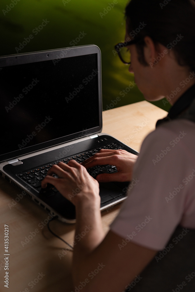 Write code and learn programming languages. A student or specialist is doing a project. The guy is a programmer working on a laptop