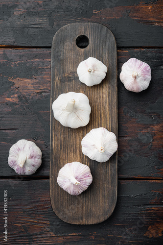 Garlic Cloves and Bulb, on wooden cutting board, on old dark wooden table background, top view flat lay