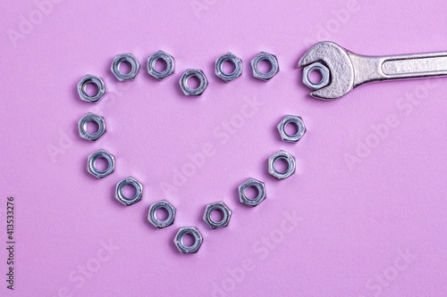 The heart of the nuts with a wrench on a purple paper background.