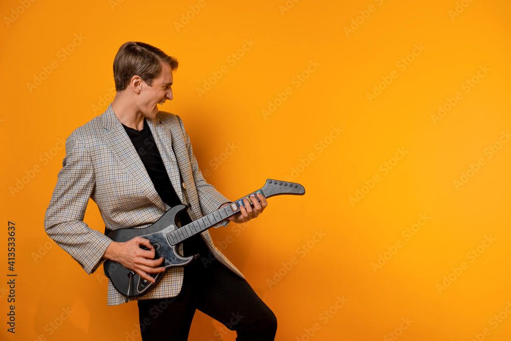 stylish and cool guy in a suit and with a game guitar on a yellow background, have fun and have a good time stylish and cool guy in a suit and with a game guitar on a yellow background, have fun and have a good time