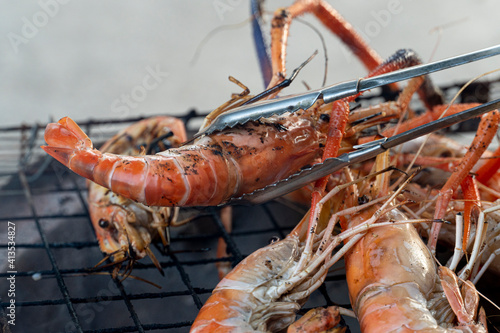 Shrimp clamps are grilled on the stove and many shrimps are arranged on the grill.