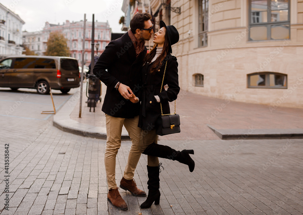 Elegant couple in love walking in the street  in Europe, having fun, kissing, hugging.