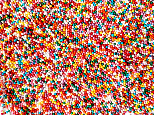 texture of multicolored sprinkles for Easter top view. different colors round small sugar balls of bright red blue and yellow colors