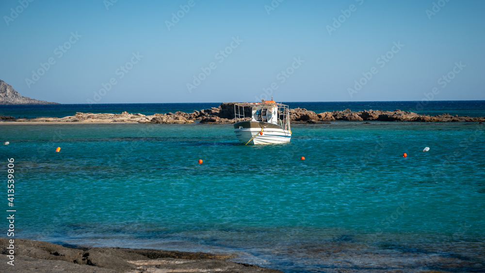 Boat in the lagoon of the famous beach Elafonisi ( or Elafonissi ) at sunny summer day. One of the best beaches in the world with pink sand. Popular touristic landmark. Crete island. Chania. Greece.