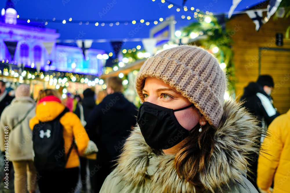 The woman is wearing a face protective mask on the Christmas market.