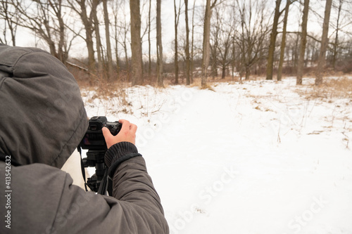 London, Canada, January 19, 2021: Editorial photo of a man in a grey jacket taking pictures outside. Winter day in London, Canada with snow on trees and ground. © Katie