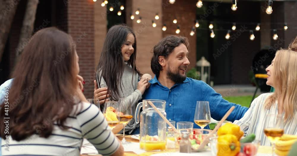 Happy Caucasian cheerful family with kids and grandfather having lunch picnic at back yard outdoors and nice communication. People of different ages spending time together at barbecue.
