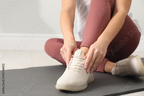 Woman wearing sport shoe on floor indoors, closeup