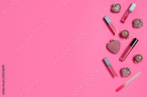 Lip glosses and Christmas ornaments on pink background, flat lay
