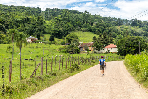 Trekking in dirty road with Farm meadow, mountain and forest around