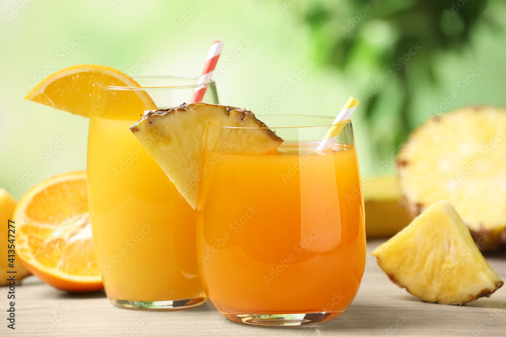 Fototapeta premium Pineapple and orange juices in glasses on white table, closeup
