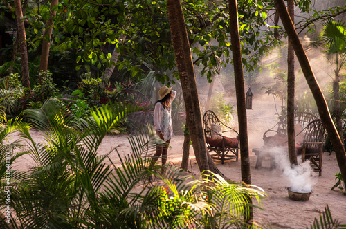 Woman stands in smoky jungle garden in Tulum