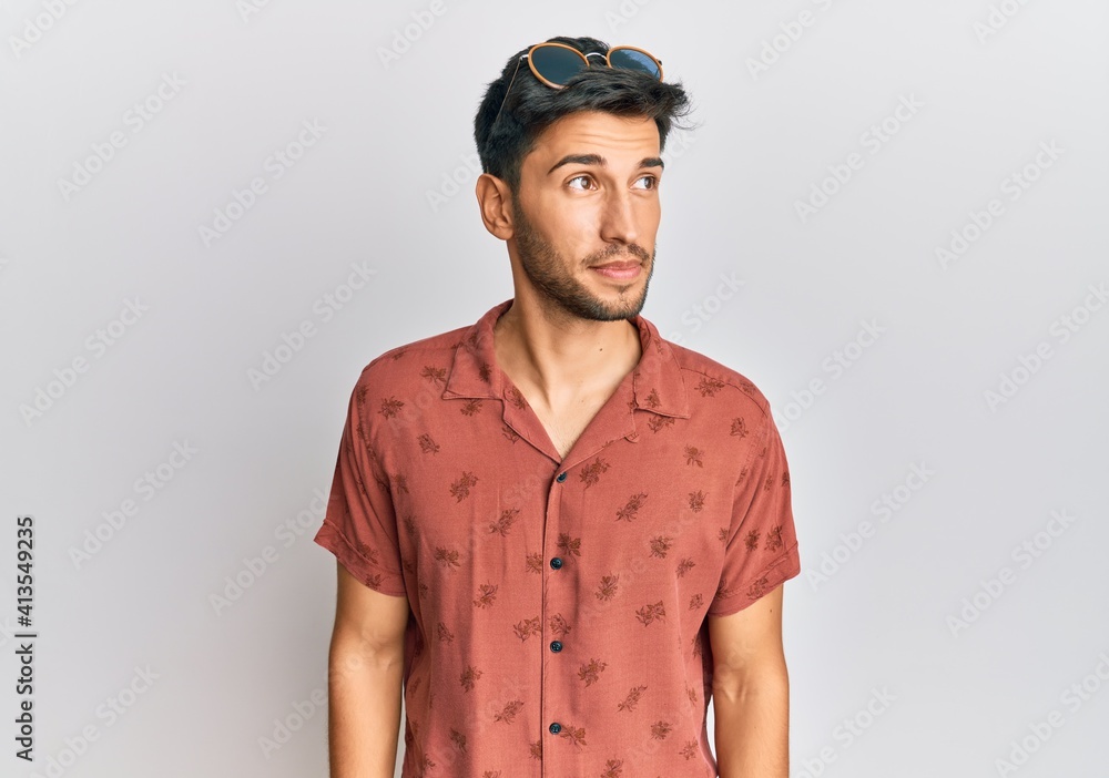 Fototapeta premium Young handsome man wearing casual summer clothes smiling looking to the side and staring away thinking.