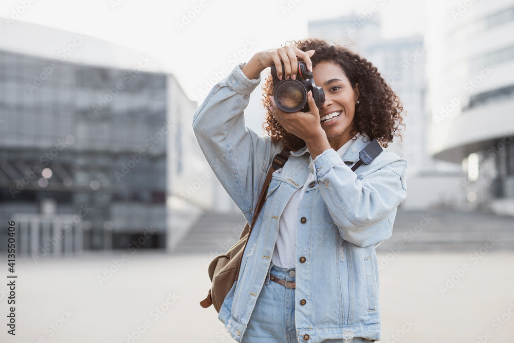 Young woman photographer takes photographs with dslr camera in a city. Travel, vacations, professional freelance work and active lifestyle concept