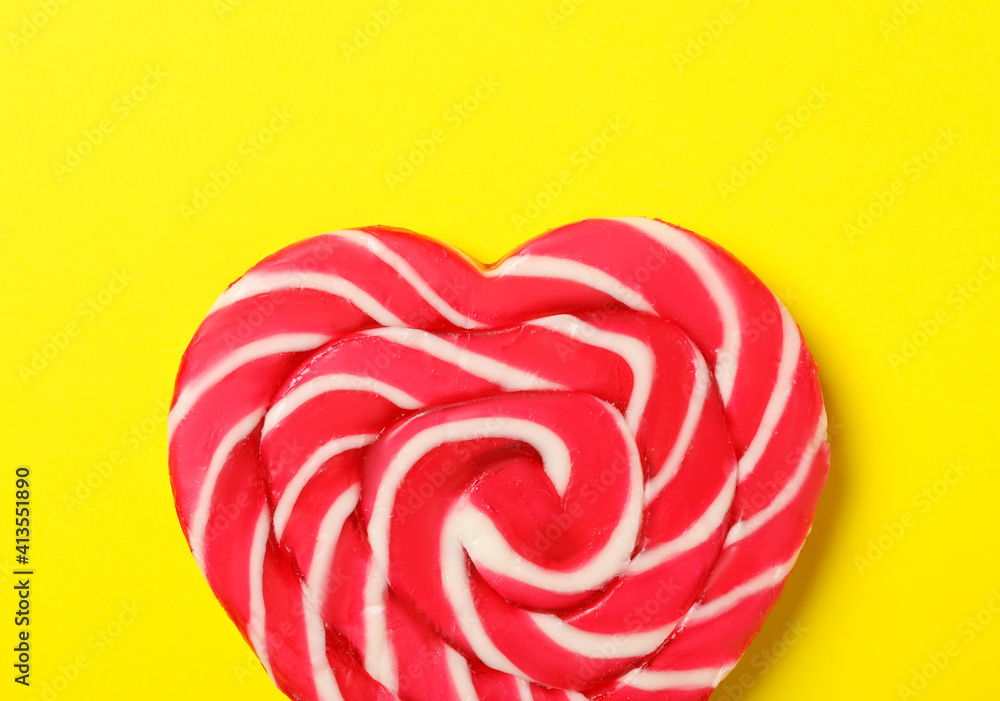 Sweet heart shaped lollipop on yellow background, top view. Valentine's day celebration
