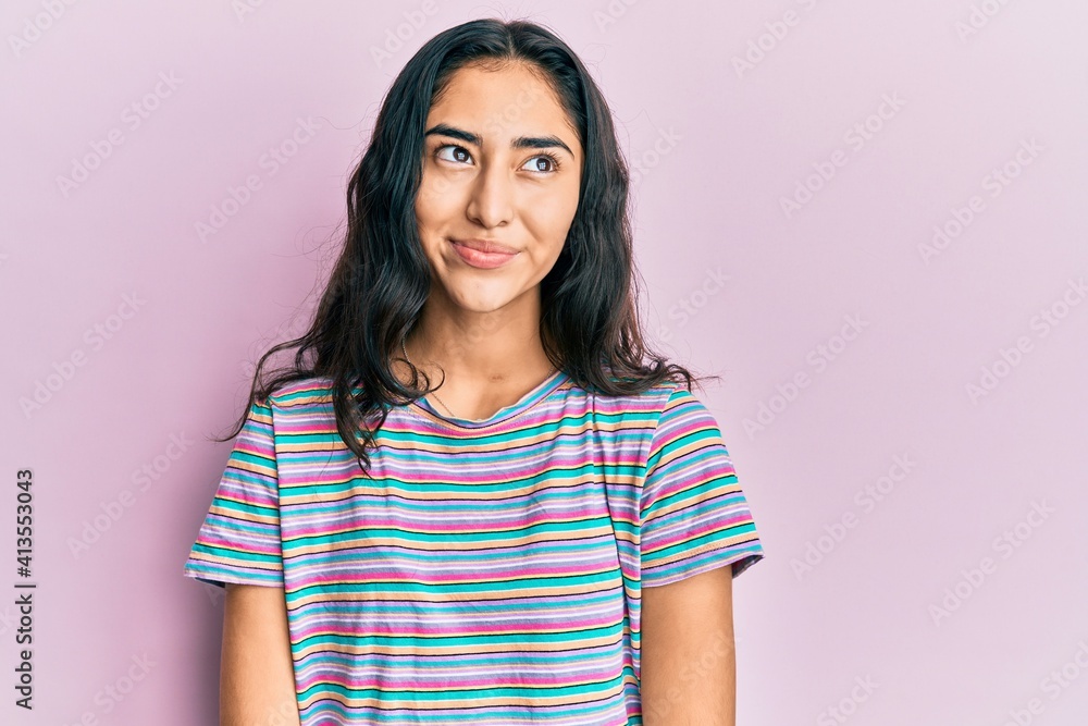 Fototapeta premium Hispanic teenager girl with dental braces wearing casual clothes smiling looking to the side and staring away thinking.