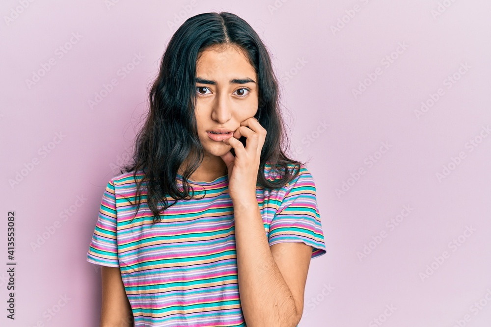 Hispanic teenager girl with dental braces wearing casual clothes looking stressed and nervous with hands on mouth biting nails. anxiety problem. Hispanic teenager girl with dental braces wearing casual clothes looking stressed and nervous with hands on mouth biting nails. anxiety problem.