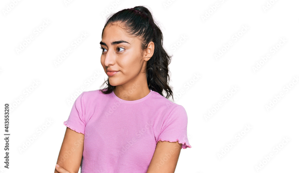 Hispanic teenager girl with dental braces wearing casual clothes looking to the side with arms crossed convinced and confident Hispanic teenager girl with dental braces wearing casual clothes looking to the side with arms crossed convinced and confident