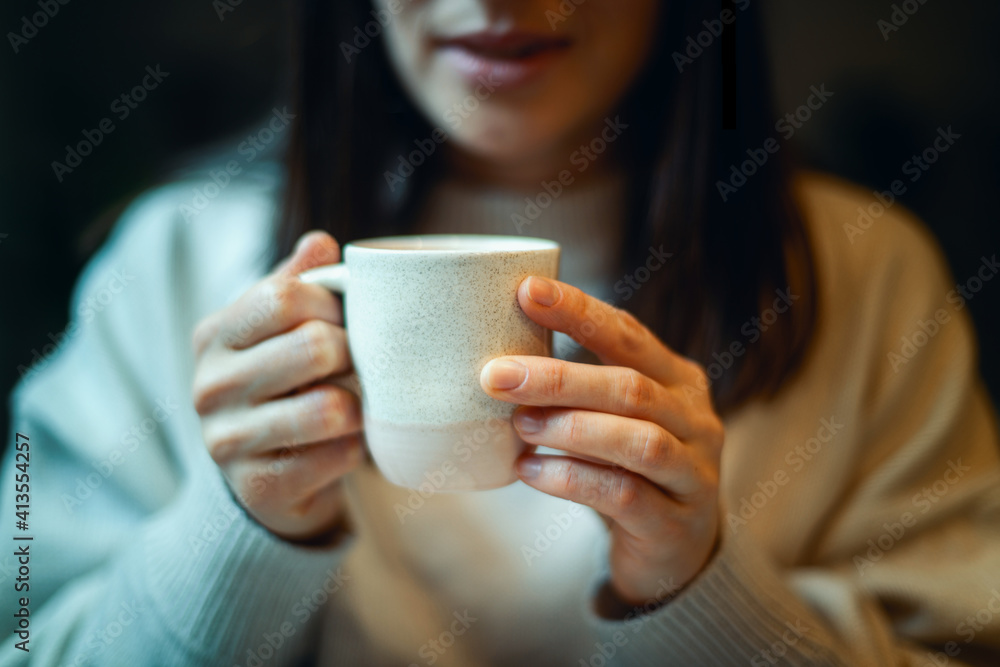 Young woman in warm sweater holding cup of coffee and planing personal goals for new year. Young woman in warm sweater holding cup of coffee and planing personal goals for new year.