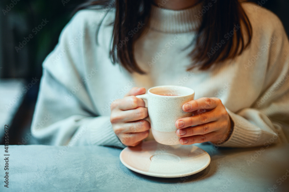 Young woman in warm sweater holding cup of coffee and planing personal goals for new year. Young woman in warm sweater holding cup of coffee and planing personal goals for new year.