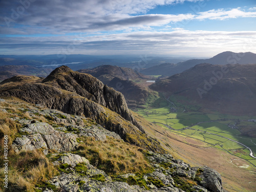 View to Loft Crag from Pike of Stickle overlooking the Great Langdale valley with Blea Tarn nestled in the fells and Windermere lake in the background, Langdale Pikes, Lake District, UK photo